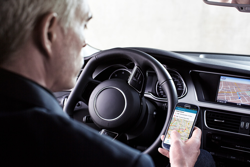 Bild zeigt Fahrer beim Nutzen eines elektronischen Fahrtenbuchs als Handy-App.